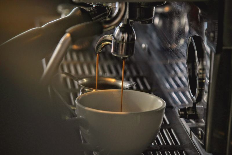 Espresso running from a steel machine into a white cup.
