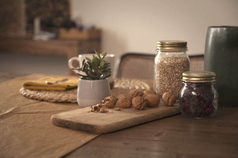 Ingredients in jars and walnuts on a wooden board in soft window light.